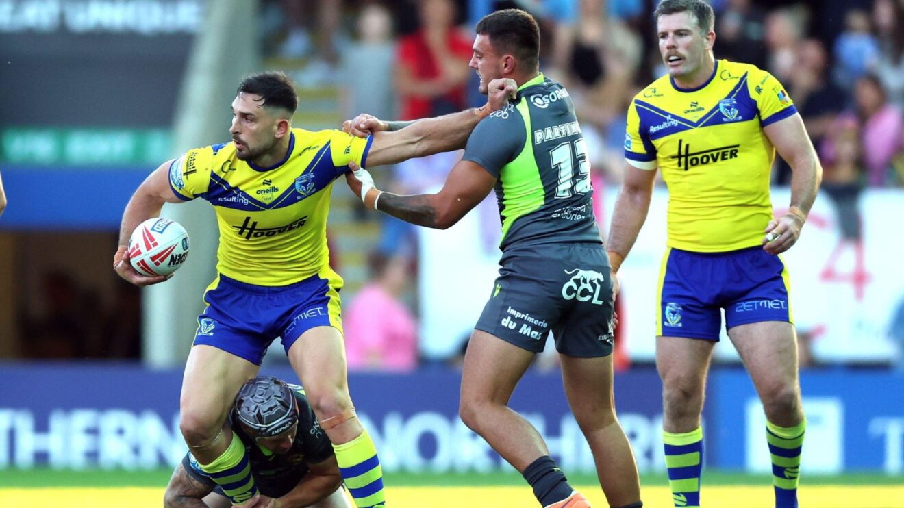Ollie Partington (in grey, making tackle) in action for Catalans Dragons in 2025