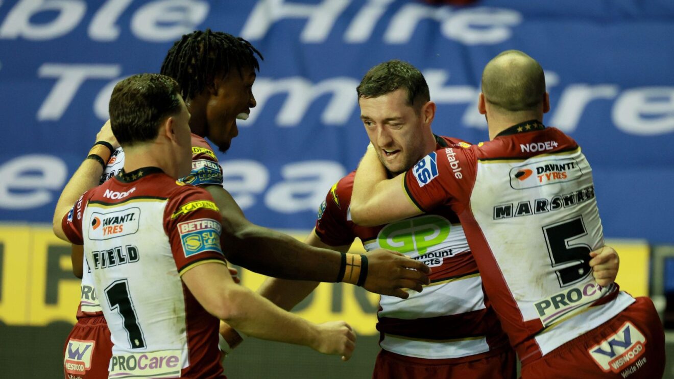 Wigan Warriors players celebrate a try in 2025