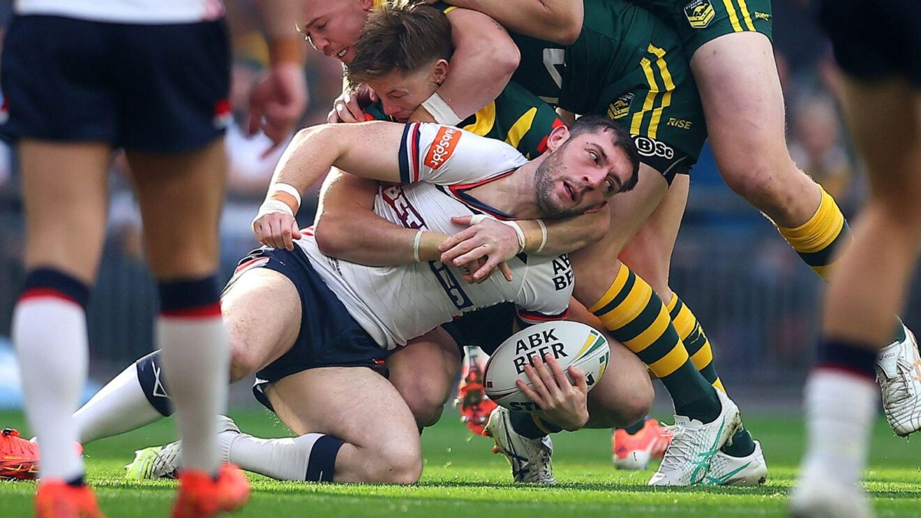 Jake Wardle in action for England in the opening Test of the 2025 Ashes Series against Australia at Wembley, being tackled to the ground by two Kangaroos players