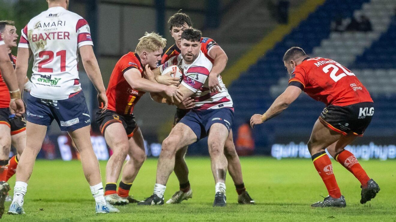 Pat Moran in action for Oldham in 2025, being tackled by three Bradford Bulls players