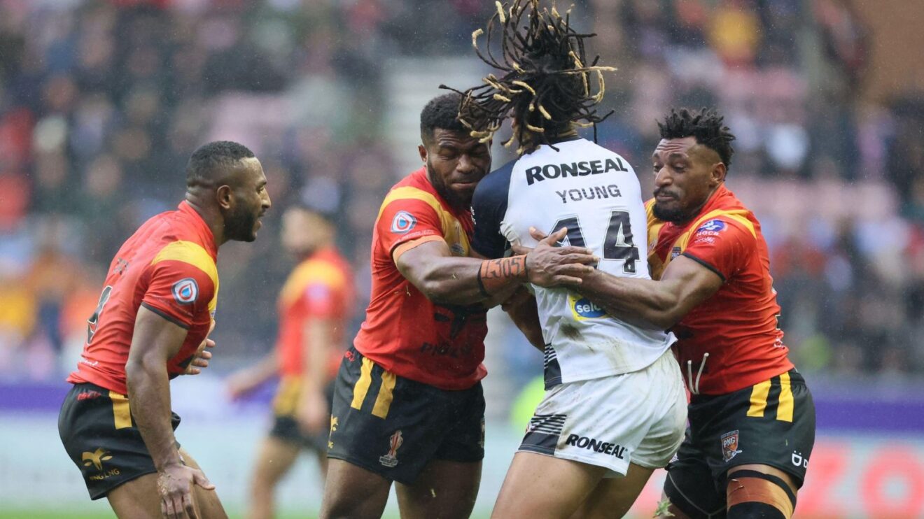 An action shot from the 2021 Rugby League World Cup quarter-final between England and Papua New Guinea, with Dom Young being tackled by numerous Kumuls defenders
