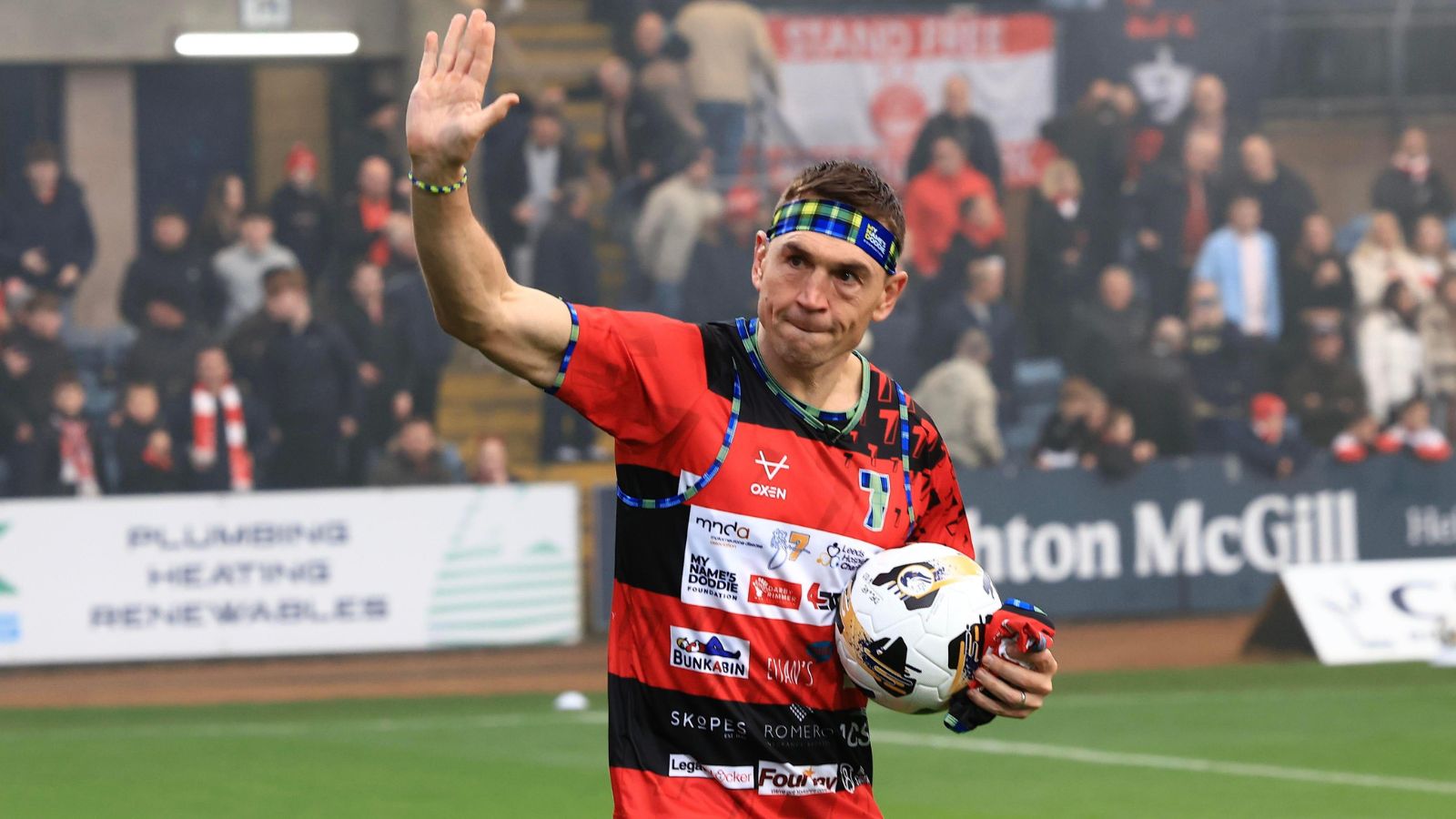 Kevin Sinfield carries the match ball onto the pitch at Dens Park ahead of Dundee FC's Scottish Premiership clash against Aberdeen in December 2025 after completing his sixth ultra-marathon during his '7 in 7: Together' challenge in 2025
