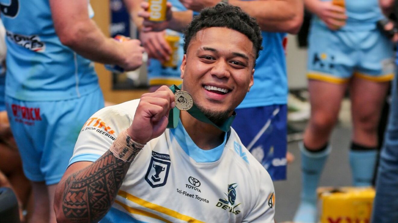 Manase Kaho celebrates Norths Devils' 2024 Queensland Cup triumph, holding up his Grand Final winners' medal to the camera
