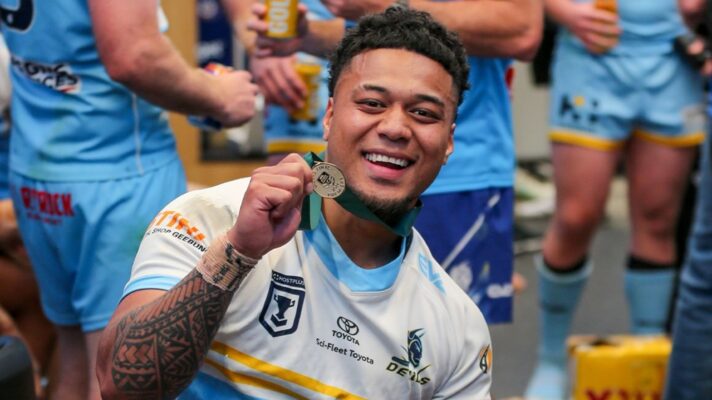 Manase Kaho celebrates Norths Devils' 2024 Queensland Cup triumph, holding up his Grand Final winners' medal to the camera