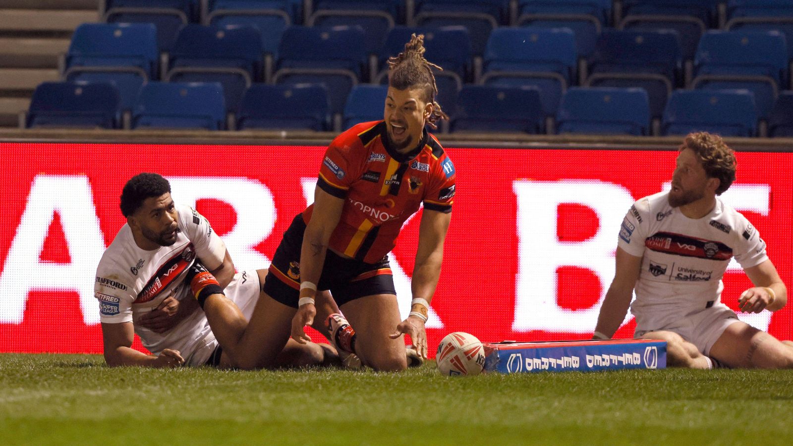 Guy Armitage celebrates a try for Bradford Bulls during a Challenge Cup tie against Salford in 2025, on the floor in the corner along with Red Devils players Kallum Watkins and Ethan Ryan