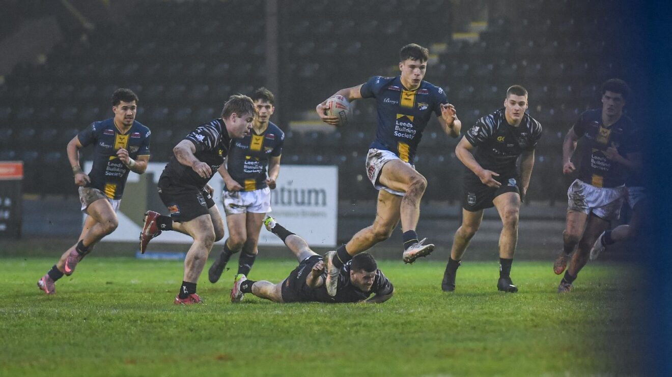 Oscar Brown in action for Leeds Rhinos during Brad Singleton's testimonial in January 2026, running through numerous Castleford Tigers defenders