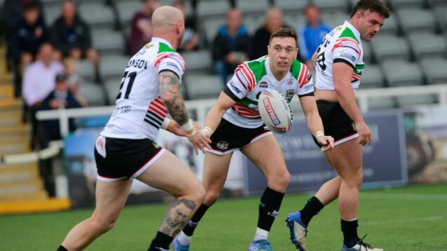 Evan Simons passes the ball to Workington Town team-mate Jordan Thomson during a game in 2022