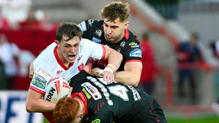 An action shot from Hull KR's win over Wigan Warriors in a Super League clash at Craven Park in May 2026, with Jack Broadbent being tackled by Finn McMillan and Shea O'Connor