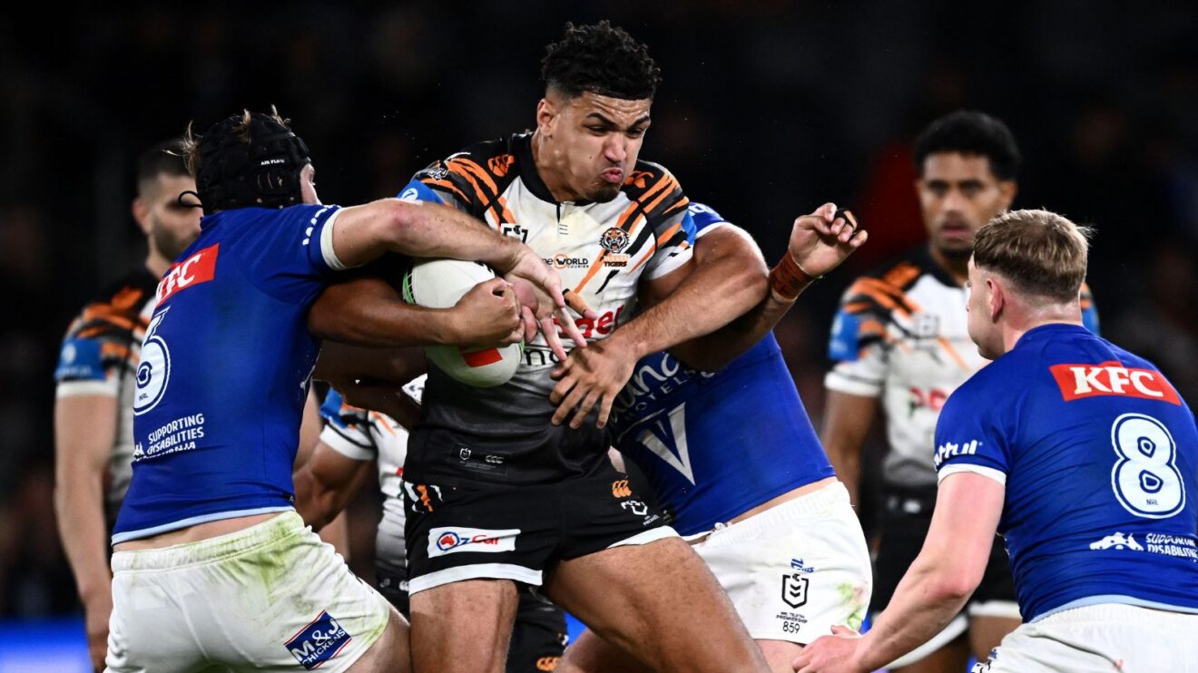 Kai Pearce-Paul in action for Wests Tigers in 2026, being tackled by two Canterbury Bulldogs players