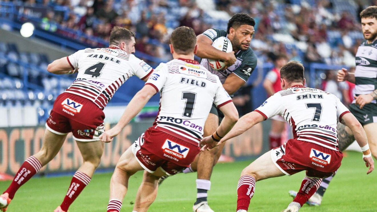 Wigan Warriors players attempting to tackle Taane Milne in 2026