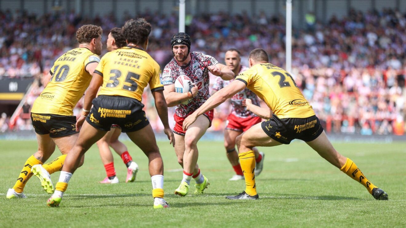 Matt Davis in action for Leigh Leopards in 2026, running the ball in at three Castleford Tigers defenders