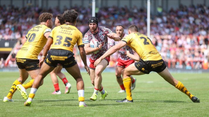 Matt Davis in action for Leigh Leopards in 2026, running the ball in at three Castleford Tigers defenders