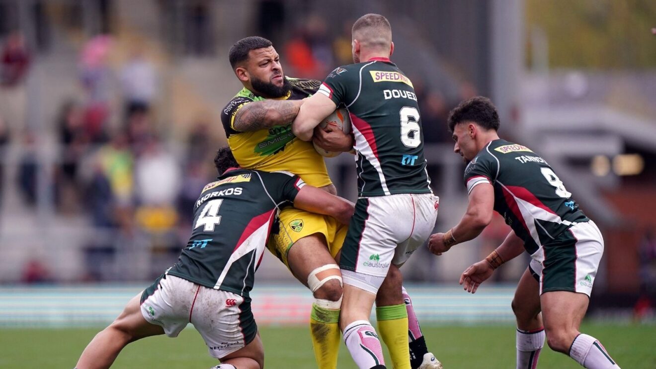 Jordan Andrade in action for Jamaica during the delayed 2021 Rugby League World Cup, being tackled by three Lebanon defenders